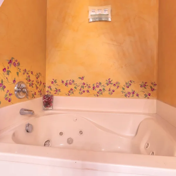 Cultura quadrada Construído em banheira de hidromassagem branca dentro de um banheiro com desenhos de flores na parede — Fotografia de Stock