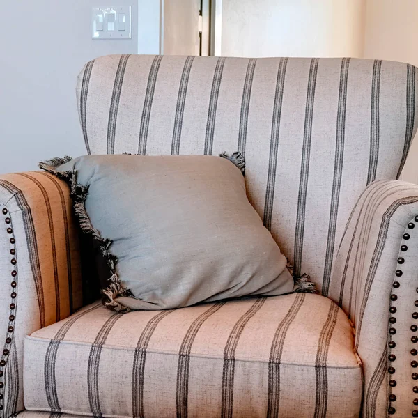 Square frame Striped armchair with fringed throw pillow inside living room with wooden floor — Stock Photo, Image