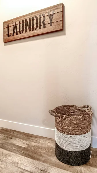 Vertical lavandaria interior sala com cesta tecida e sinal de madeira decorativo contra a parede — Fotografia de Stock