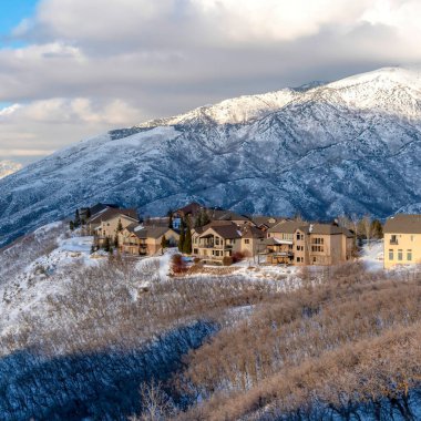 Wasatch Dağları 'nın karlı arazisinde, arka planda günışığı zirvesi olan kare ekin evleri