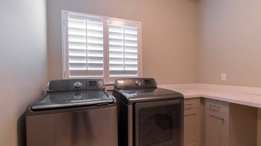 Çamaşırhanede panorama metalik çamaşır makinesi ve kurutucu.