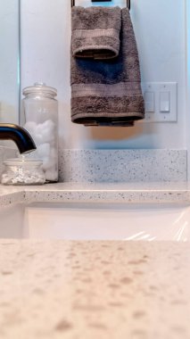 Banyo lavabosunun üzerinde dikey siyah bir musluk ayna ve duvara asılı bir havlu.