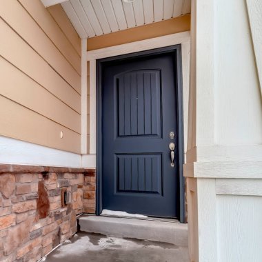 Kare çerçeve Mavi kapılı ev girişi ve taş tuğlalı ve ahşap kaplamalı duvar