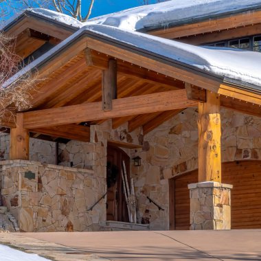 Park City Utah 'daki Square Home' da karlı gable çatıları taş duvarları ve açık hava merdivenleri var.