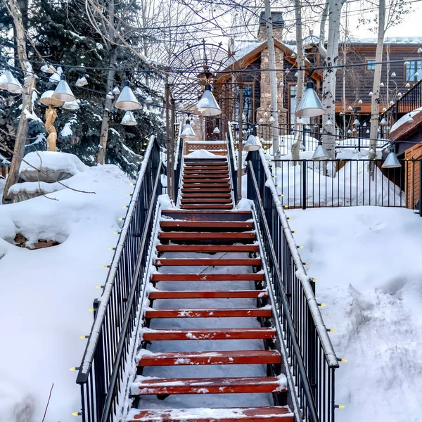 Recorte cuadrado Escalera en la ladera nevada con edificios y árboles bajo el cielo nublado de invierno — Foto de Stock