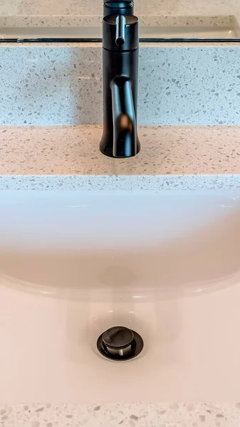 Vertikale Ernte Nahaufnahme eines Waschbeckens mit schwarzem Wasserhahn auf weißer Arbeitsplatte — Stockfoto