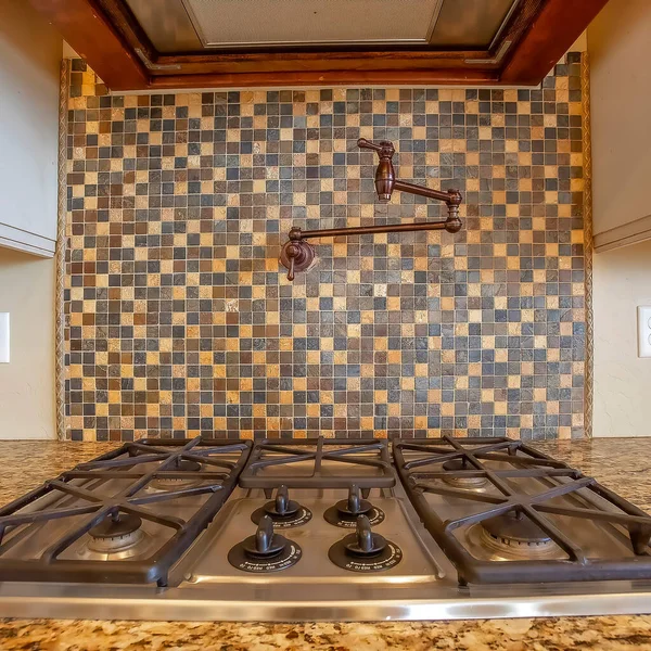 Quadratische Kochplatte und Dunstabzugshaube in der Küche mit Wasserhahn an der Fliesenwand — Stockfoto