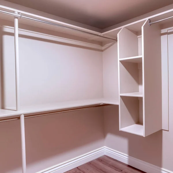 Square Spacious walk in closet of new home with metal rods shelves and wooden floor