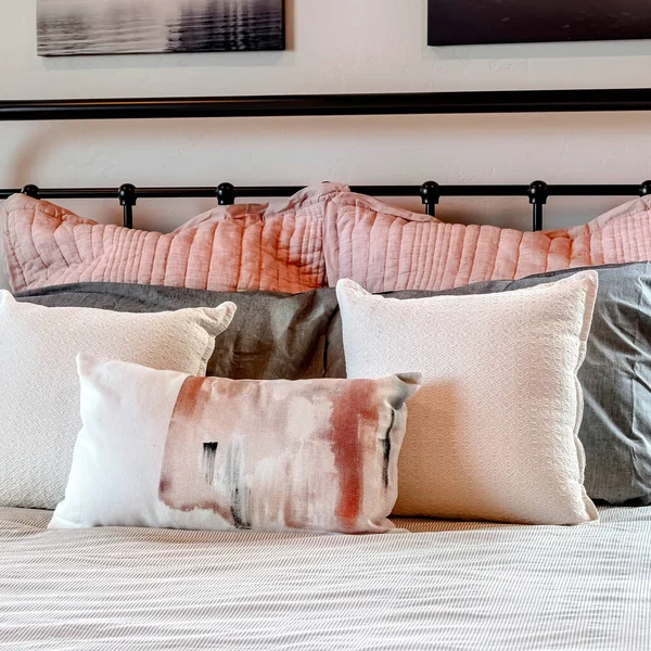 Square Single bed with fluffy pillows against black metal headboard inside bedroom — Stock Photo, Image