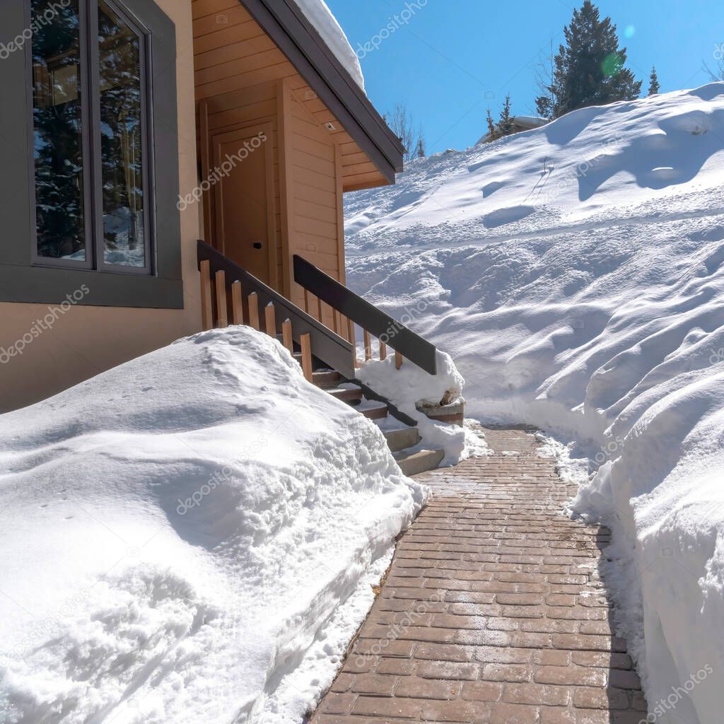 Square Stone brick pathway and stairs leading to home entrance amid deep layer of snow