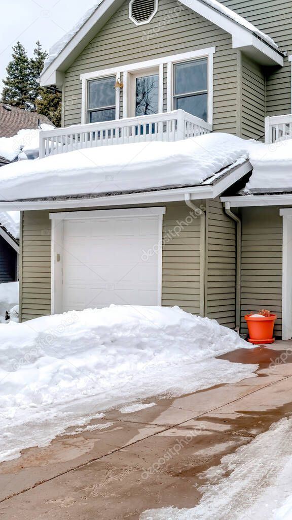 Vertical frame Facade of home with snowy driveways in front of two car garage viewed in winter