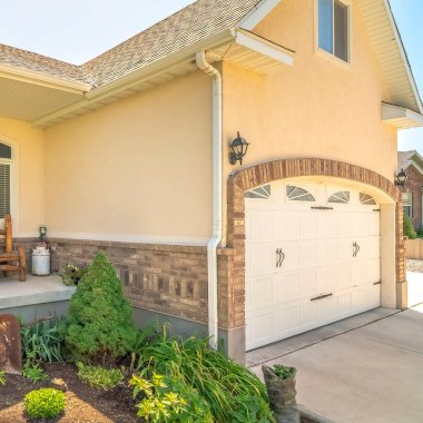 Kare ev cephesi kemerli garaj kapısı ve oval cam camlı ön kapı.