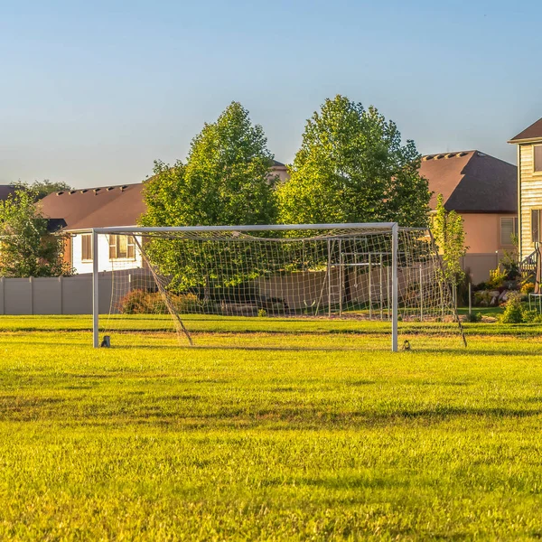 Fútbol cuadrado gol en el vasto campo de hierba verde en frente de las casas vistas en un día soleado —  Fotos de Stock