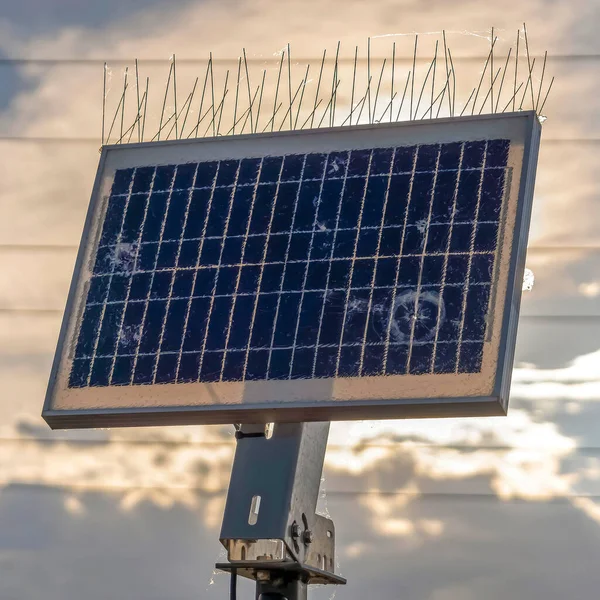 Квадратная солнечная панель с тонкими проводами на фоне живописного неба с белыми и темными облаками — стоковое фото