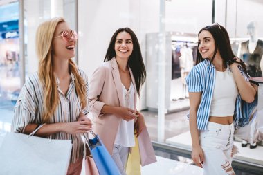 Üç çekici genç kızlar modern alışveriş merkezinde alışveriş torbaları ile alışveriş yapıyoruz.