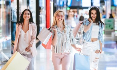 Üç çekici genç kızlar modern alışveriş merkezinde alışveriş torbaları ile alışveriş yapıyoruz.