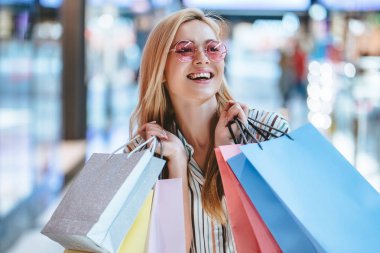 Çekici genç mutlu kadın modern alışveriş merkezinde alışveriş torbaları ile alışveriş yapıyor.