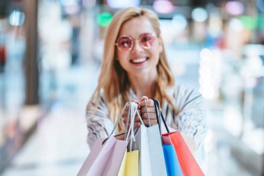 Çekici genç mutlu kadın modern alışveriş merkezinde alışveriş torbaları ile alışveriş yapıyor.