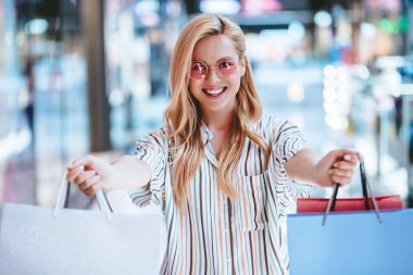 Çekici genç mutlu kadın modern alışveriş merkezinde alışveriş torbaları ile alışveriş yapıyor.