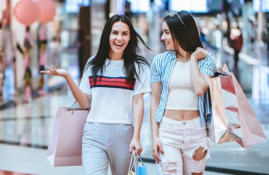 İki çekici genç kızlar modern alışveriş merkezinde alışveriş torbaları ile alışveriş yapıyoruz.