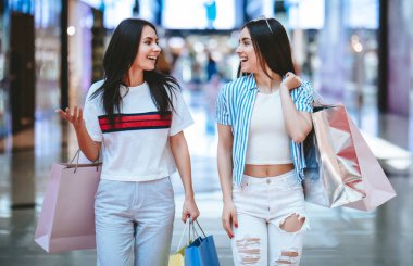 İki çekici genç kızlar modern alışveriş merkezinde alışveriş torbaları ile alışveriş yapıyoruz.