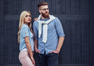 Şık genç çift zaman açık havada birlikte geçiriyor. Çekici kadın ve sakallı yakışıklı siyah ahşap arka plan üzerine poz.