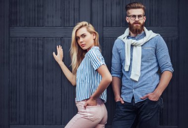 Şık genç çift zaman açık havada birlikte geçiriyor. Çekici kadın ve sakallı yakışıklı siyah ahşap arka plan üzerine poz.