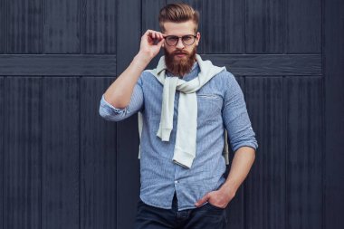 Şık sakallı adam şehrin siyah ahşap zemin üzerine poz. Genç adam izole göz gözlük.