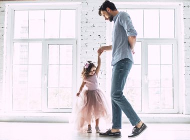 Seni seviyorum, baba! Yakışıklı genç adam evde küçük şirin kızı ile dans ediyor. Mutlu babalar günü!