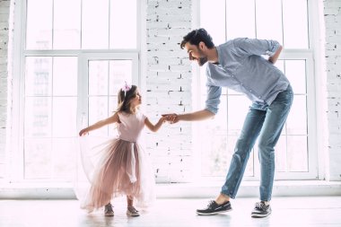 Seni seviyorum, baba! Yakışıklı genç adam evde küçük şirin kızı ile dans ediyor. Mutlu babalar günü!