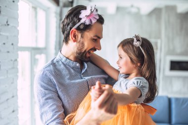 Seni seviyorum, baba! Yakışıklı genç adam evde etek giyen küçük şirin kızı ile dans ediyor. Mutlu babalar günü!