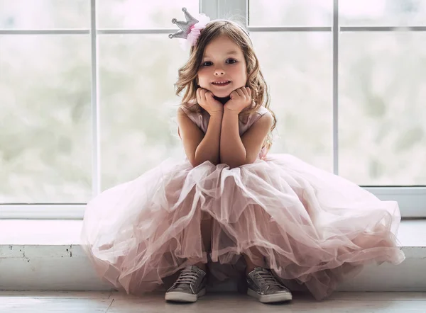 小可爱的女孩穿着漂亮的礼服坐在窗口附近在家 — 图库照片