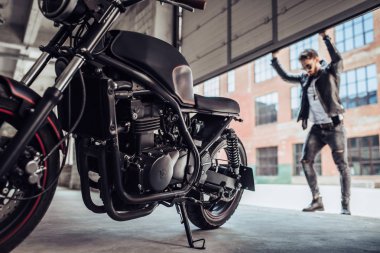 Klasik tarzı siyah motosiklet ile yakışıklı sakallı motorcu. Cafe yarış garaj içinde.