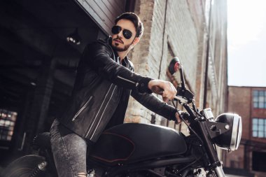 Klasik tarzı siyah motosiklet ile yakışıklı sakallı motorcu. Cafe yarış garaj içinde.