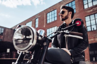 Klasik tarzı siyah motosiklet ile yakışıklı sakallı motorcu. Cafe racer.