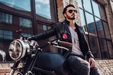 Klasik tarzı siyah motosiklet ile yakışıklı sakallı motorcu. Cafe racer.