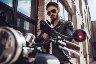 Klasik tarzı siyah motosiklet ile yakışıklı sakallı motorcu. Cafe racer.