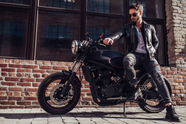 Klasik tarzı siyah motosiklet ile yakışıklı sakallı motorcu. Cafe racer.