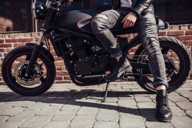 Klasik tarzı siyah motosiklet ile yakışıklı sakallı motorcu görüntü kırpılmış. Cafe racer.
