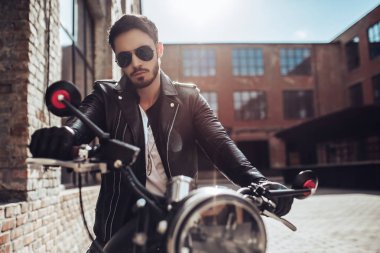 Klasik tarzı siyah motosiklet ile yakışıklı sakallı motorcu. Cafe racer.