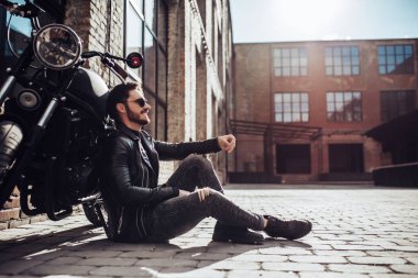 Klasik tarzı siyah motosiklet ile yakışıklı sakallı motorcu. Cafe racer.