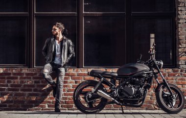 Klasik tarzı siyah motosiklet ile yakışıklı sakallı motorcu. Cafe racer.