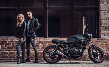 Romantik motorcu çift siyah motosiklet ile. Yakışıklı adam ve genç çekici kadın kafe racer ile açık havada sakallı.