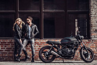 Romantik motorcu çift siyah motosiklet ile. Yakışıklı adam ve genç çekici kadın kafe racer ile açık havada sakallı.