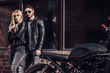 Romantik motorcu çift siyah motosiklet ile. Yakışıklı adam ve genç çekici kadın kafe racer ile açık havada sakallı.