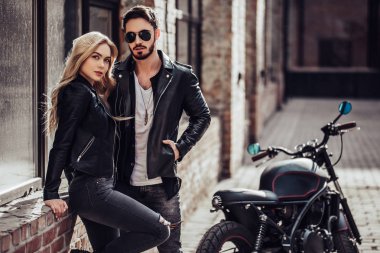 Romantik motorcu çift siyah motosiklet ile. Yakışıklı adam ve genç çekici kadın kafe racer ile açık havada sakallı.