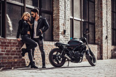 Romantik motorcu çift siyah motosiklet ile. Yakışıklı adam ve genç çekici kadın kafe racer ile açık havada sakallı.