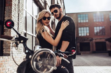 Romantik motorcu çift siyah motosiklet ile. Yakışıklı adam ve genç çekici kadın kafe racer ile açık havada sakallı.