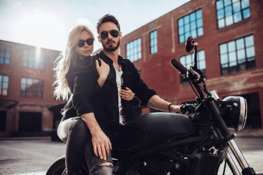 Romantik motorcu çift siyah motosiklet ile. Yakışıklı adam ve genç çekici kadın kafe racer ile açık havada sakallı.