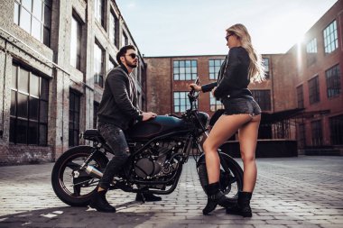 Romantik motorcu çift siyah motosiklet ile. Yakışıklı adam ve genç çekici kadın kafe racer ile açık havada sakallı.